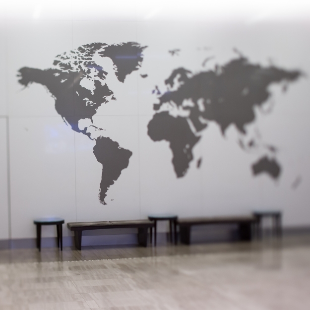 Stifel Home Office Interior shot of a dark gray world map on the wall behind benches 
